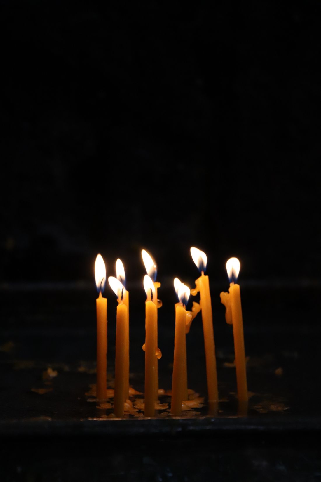 Thin beeswax candles burning in the dark